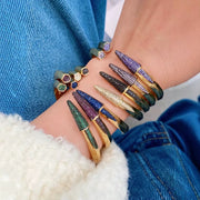 Colorful stiletto-shaped bracelets on a wrist with a blue denim background